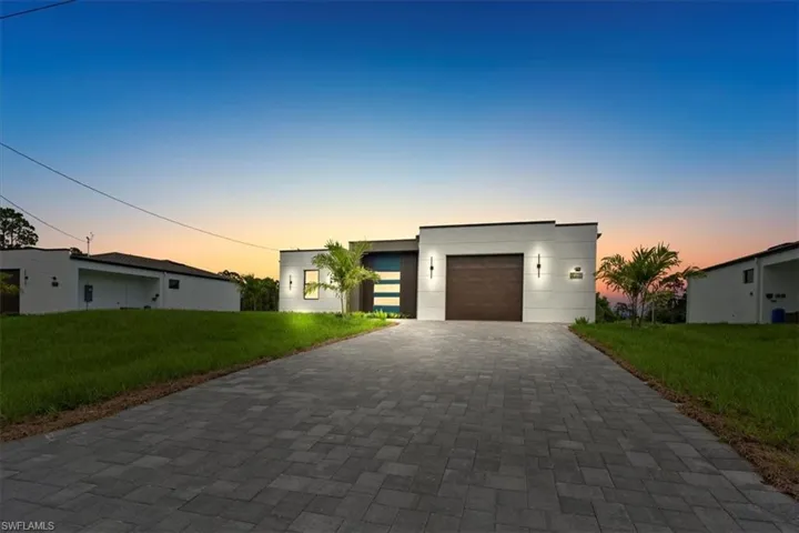 Contemporary home with a yard, decorative driveway, and a garage