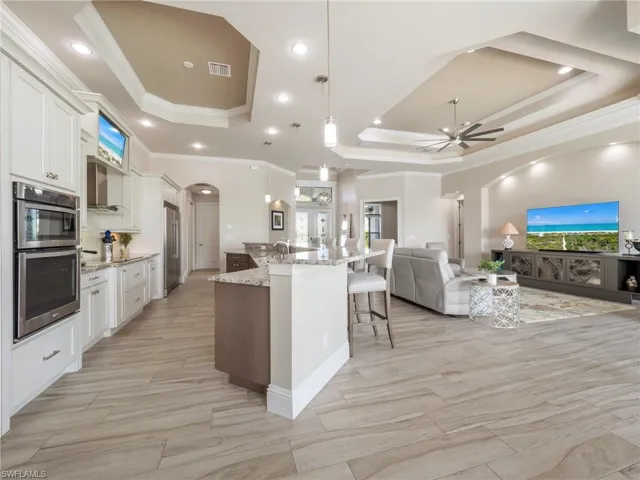 Kitchen with white cabinetry, open floor plan, a large island, a tray ceiling, and pendant lighting