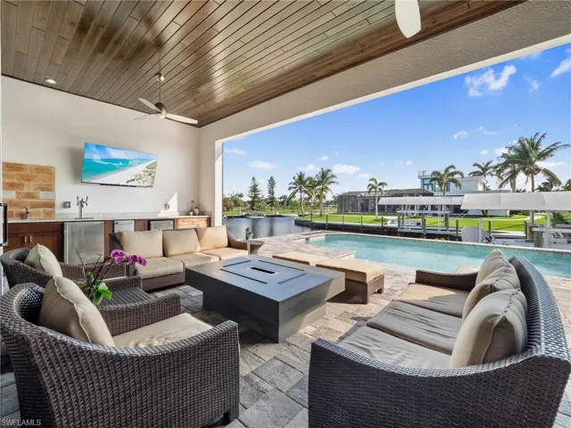 View of patio featuring a ceiling fan, a sink, exterior kitchen, an outdoor pool, and an outdoor living space