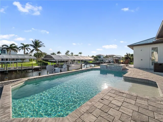 View of swimming pool with a water view, a pool with connected hot tub, and a patio