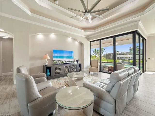 Living area featuring a ceiling fan, a raised ceiling, and crown molding