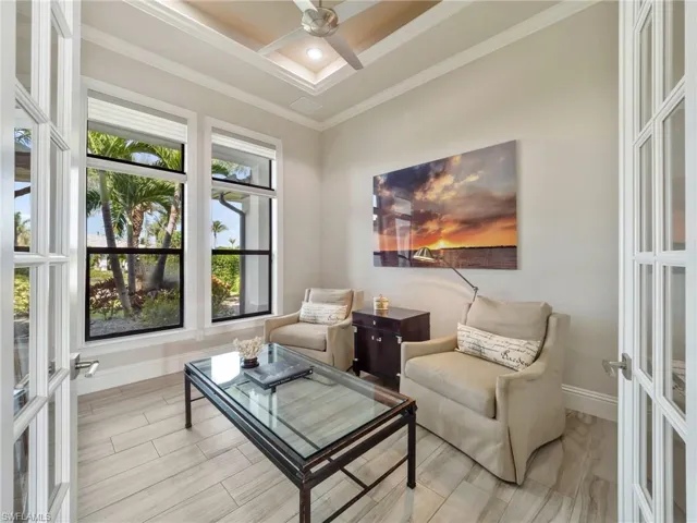 Living area featuring ceiling fan, baseboards, crown molding, and french doors