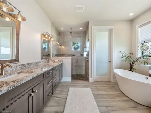 Bathroom with double vanity, a shower stall, a freestanding bath, and a sink