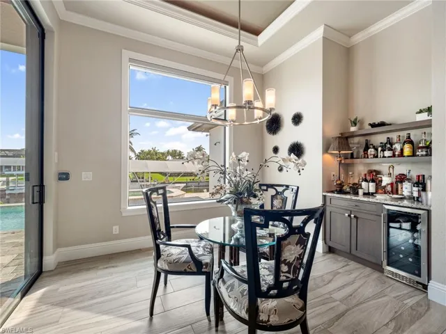 Dining space with wine cooler, an inviting chandelier, a dry bar, and crown molding