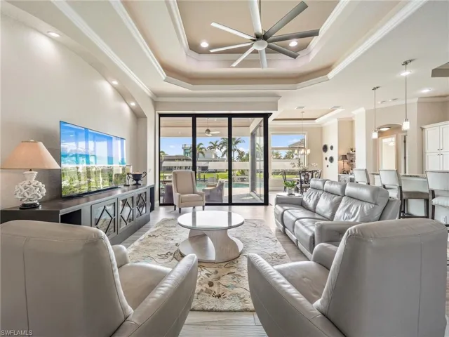 Living room featuring ceiling fan, light wood-style floors, a raised ceiling, and crown molding