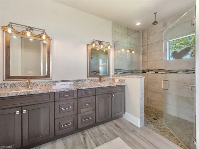 Bathroom with double vanity, a stall shower, and a sink