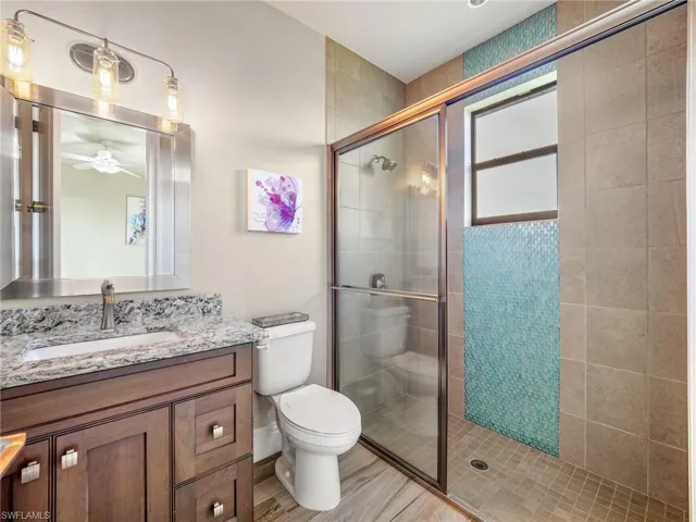 Full bathroom featuring toilet, a shower stall, ceiling fan, and vanity