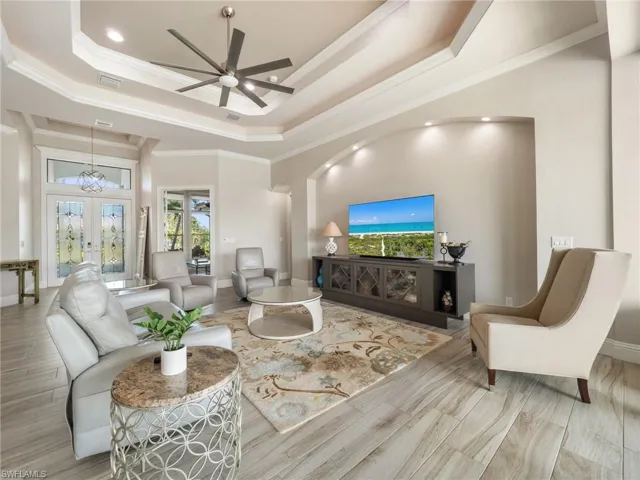 Living room with visible vents, baseboards, french doors, ornamental molding, and a raised ceiling