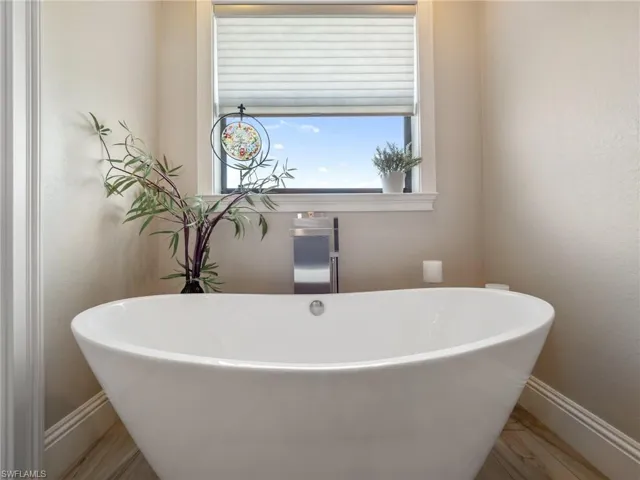 Bathroom with wood finished floors, a freestanding tub, and baseboards