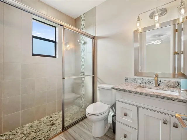 Full bathroom featuring toilet, a shower stall, and vanity