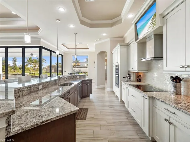 Kitchen with a tray ceiling, white cabinets, and pendant lighting