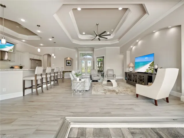 Living area featuring ceiling fan, ornamental molding, a raised ceiling, and baseboards