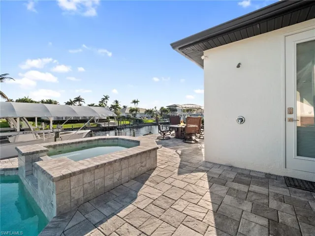 Outdoor pool with an in ground hot tub, outdoor dining space, a patio, and a water view