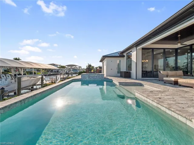 View of pool with a ceiling fan, a pool with connected hot tub, and boat lift