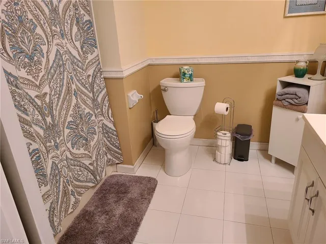 Full bath with toilet, vanity, tile patterned floors, a shower with curtain, and baseboards