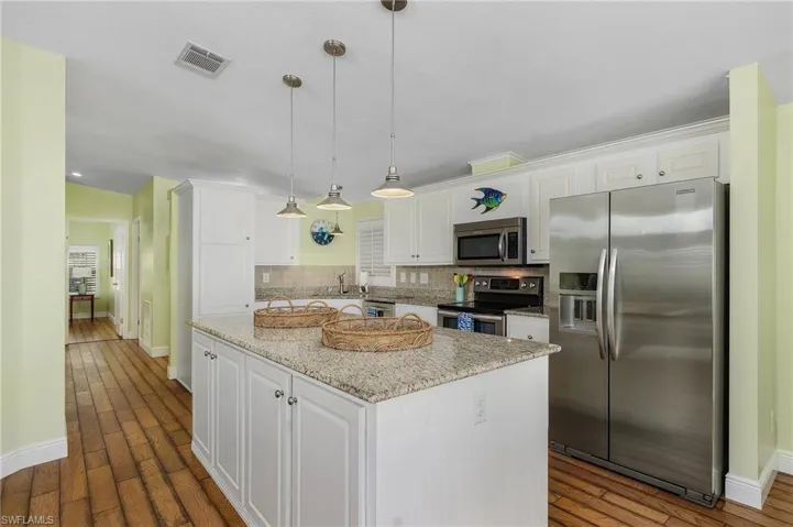 Kitchen with stainless steel appliances, baseboards, visible vents, and white cabinetry