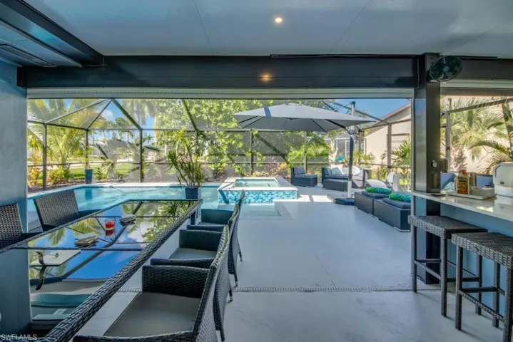View of patio featuring an outdoor lounge area with bar, a sunroom, a pool with connected hot tub, and glass enclosure