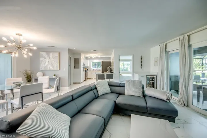 Living room featuring suspended lighting, light marble finish floors, and wine cooler