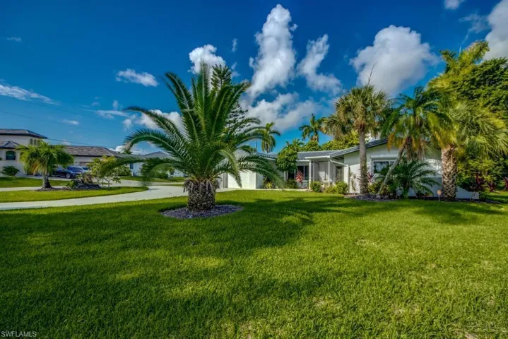 View of green lawn with a garage and driveway
