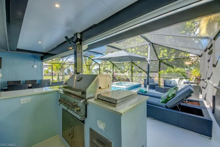 View of patio with a sunroom, glass enclosure, and an outdoor kitchen with living area