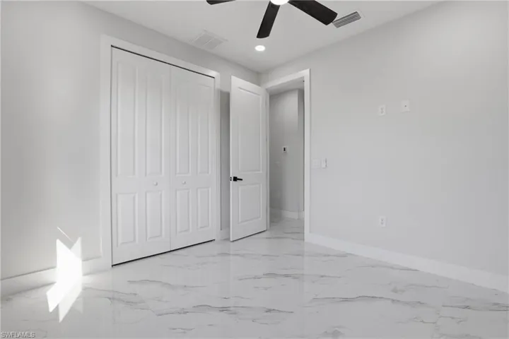 Unfurnished bedroom featuring light marble finish floors, a closet, ceiling fan, and recessed lighting