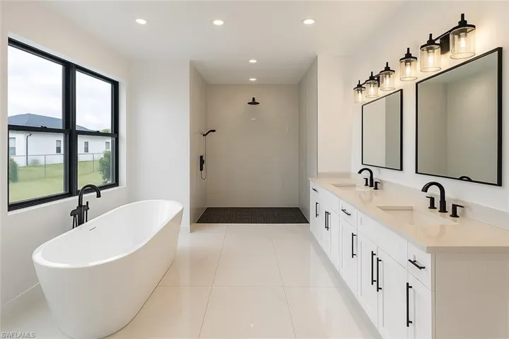 Full bath featuring a freestanding bath, a tile shower, recessed lighting, double vanity, and light tile patterned floors