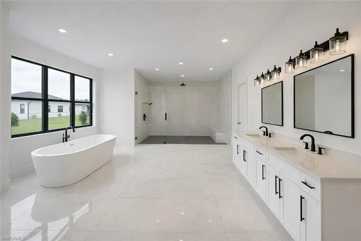 Bathroom featuring a shower stall, a freestanding bath, double vanity, and recessed lighting