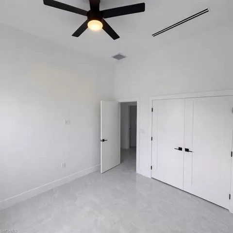 Unfurnished bedroom featuring ceiling fan, a closet, and a high ceiling