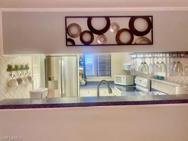 Kitchen view of white appliances, backsplash, and dark countertops