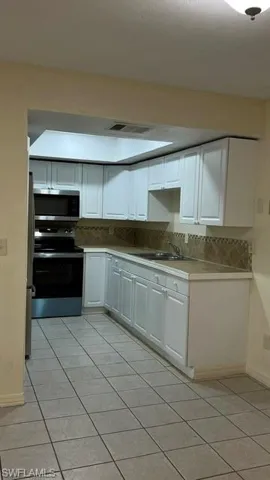 Kitchen featuring white cabinetry, tile backsplash, built-in stainless steel appliances, and a skylight