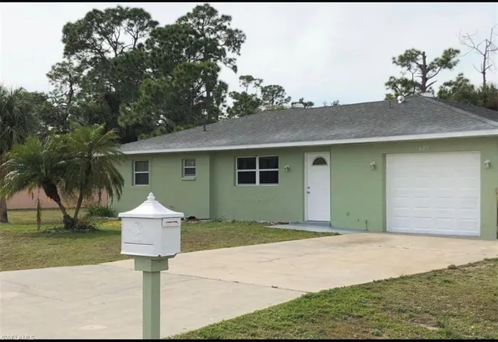 Single-story residence featuring a light green exterior, an attached garage with a white door, and a concrete driveway