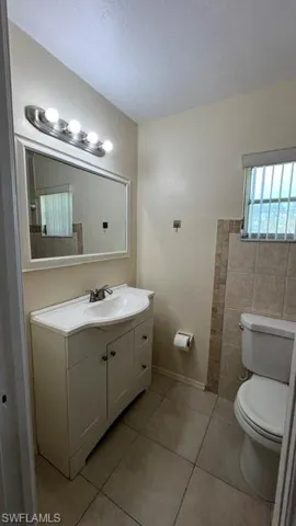 Bathroom featuring a single vanity with storage, a rectangular mirror, and a toilet