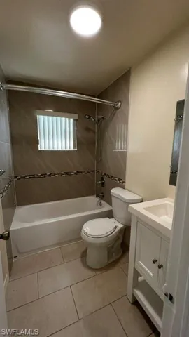 Bathroom featuring a white bathtub, toilet, and vanity with an integrated sink