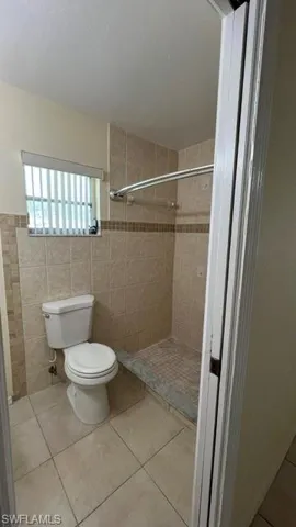 Bathroom featuring neutral-toned tile flooring and wall tiling with a decorative border