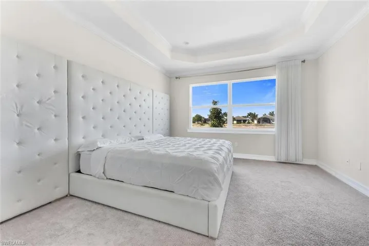 Carpeted bedroom featuring crown molding and a tray ceiling