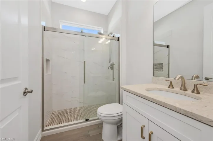 Bathroom with vanity and a marble finish shower