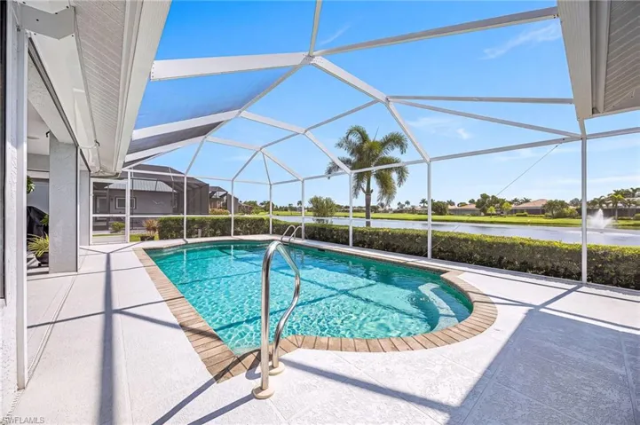 Screened-in outdoor pool featuring a water backdrop and a spacious patio