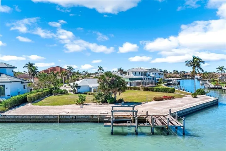 View of dock featuring a residential view, boat lift, a water view, and a yard