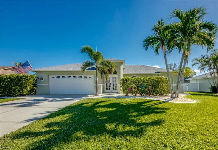 View of front of property with a front lawn, a garage, and french doors