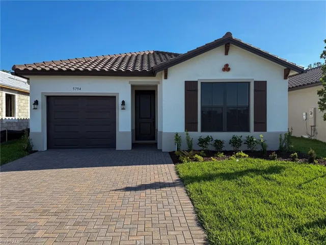 View of front of house with a tile roof, decorative driveway, a front lawn, an attached garage, and stucco siding