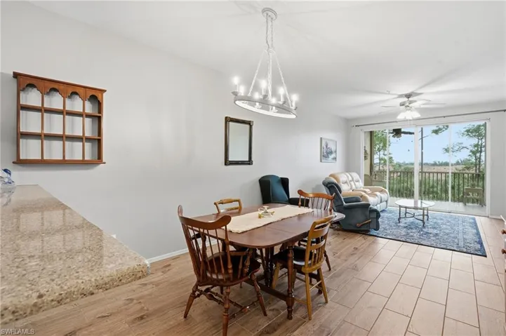 Dining space with a ceiling fan, light wood-type flooring, and suspended lighting