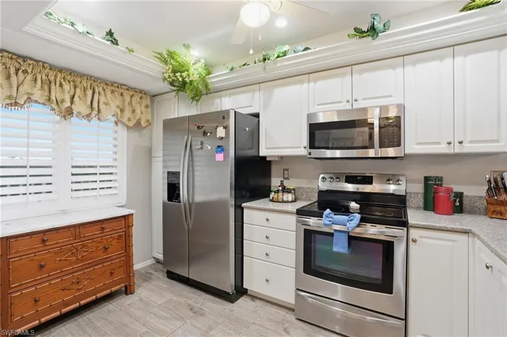 Kitchen with stainless steel appliances, white cabinets, and ceiling fan