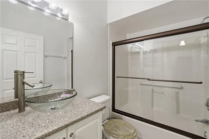 Bathroom with vanity and enclosed tub / shower combo