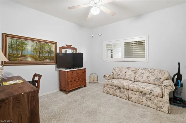 Living area with light colored carpet and a ceiling fan