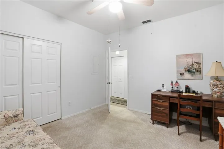 Bedroom with a desk, light colored carpet, ceiling fan, and a closet