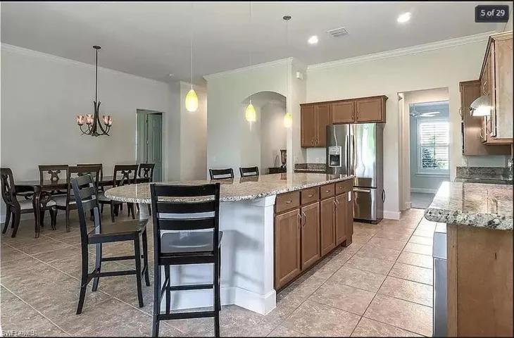 Bright and open kitchen featuring granite countertops, wood cabinetry, and a large island.