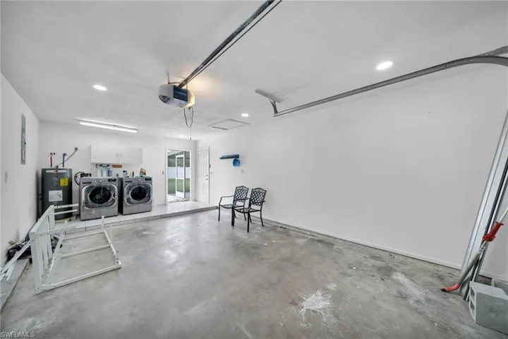 Garage featuring separate washer and dryer, electric water heater, a garage door opener, and recessed lighting