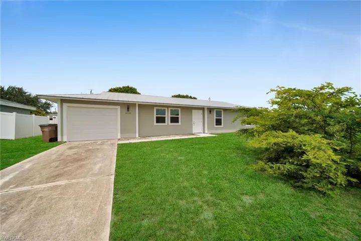 Ranch-style home with driveway, a garage, stucco siding, and a metal roof