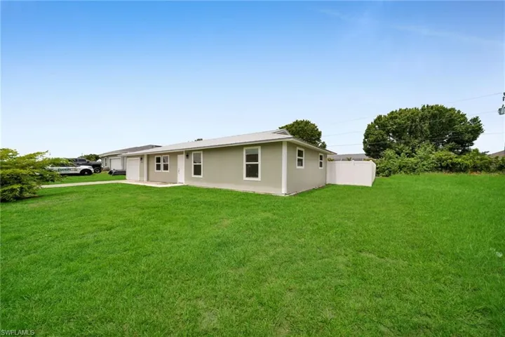 Rear view of property featuring an attached garage, a lawn, and driveway