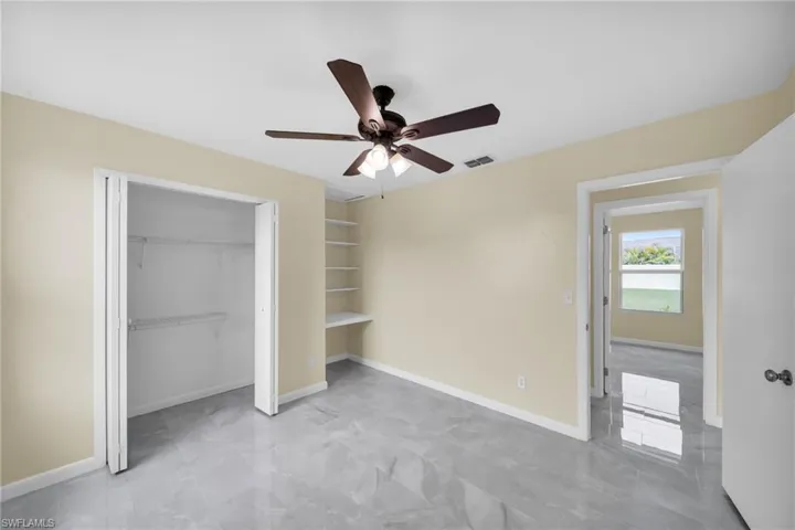 Unfurnished bedroom featuring light marble finish floors, a closet, and ceiling fan